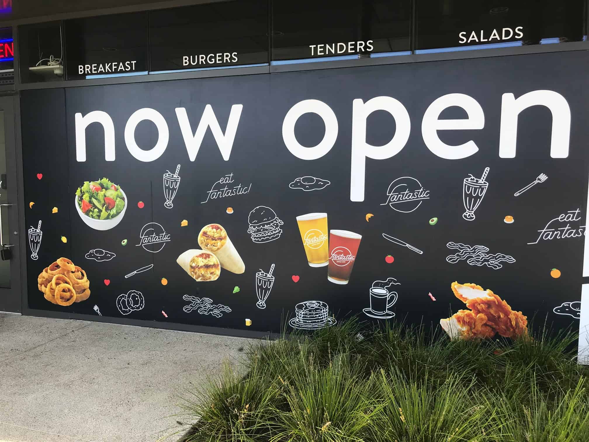 a sign that says now open on the side of a building.