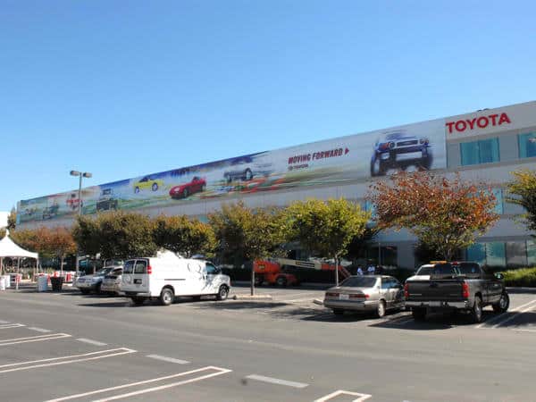 Toyota celebrating 50th anniversary How do you celebrate your 50th anniversary when you have over 1000 employees? Toyota threw this parking lot party and wanted to appropriately decorate their buildings. This giant continuous banner extends over 200 feet and features a timeline of their most popular vehicles.