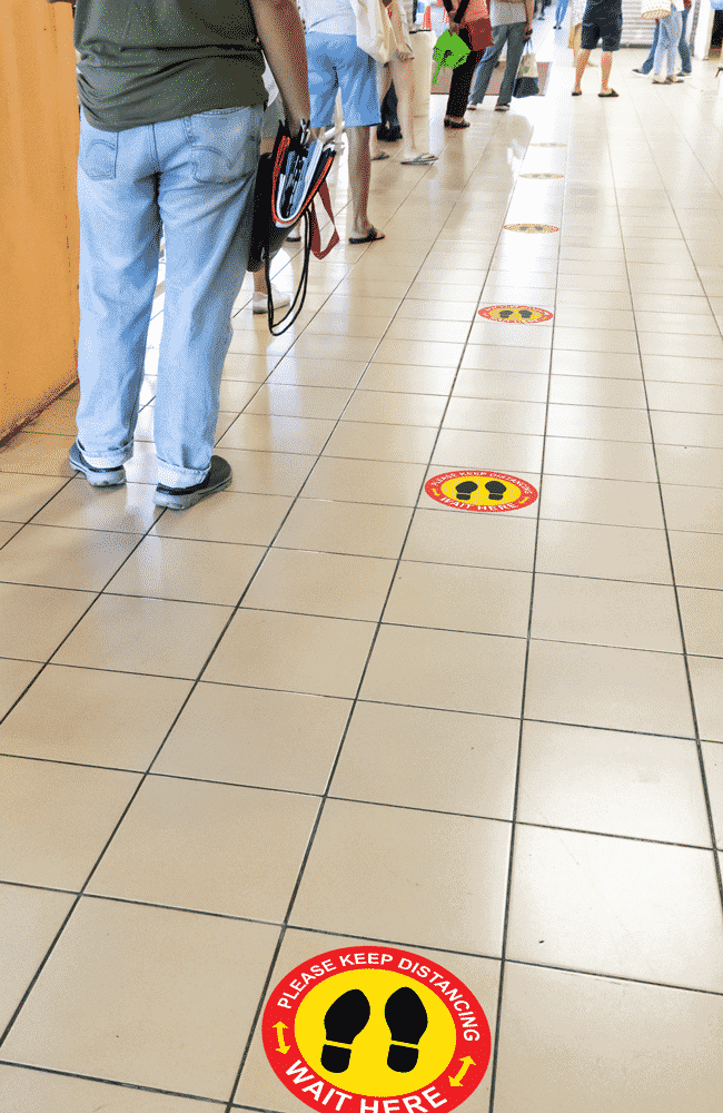 Individuals in line spaced out with social distancing stickers