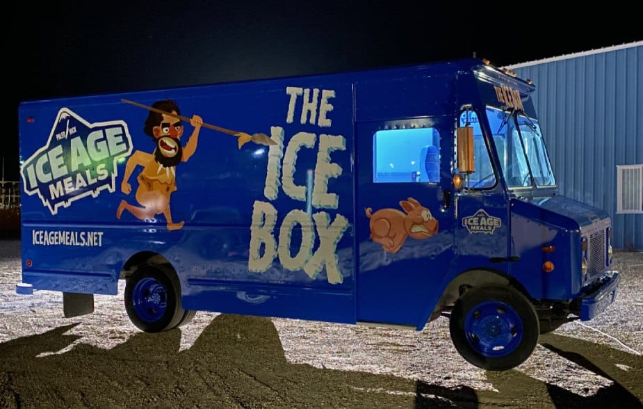 a blue ice box truck parked in front of a building.