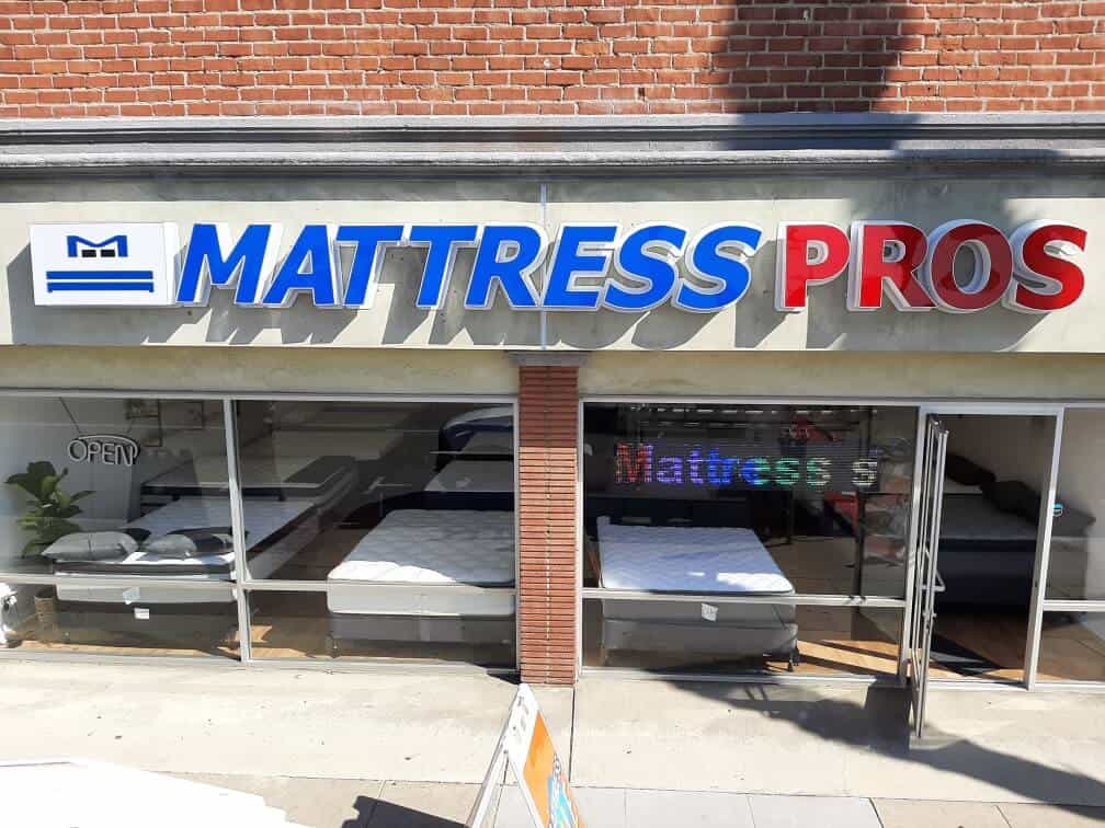 Mattress Pros New Sign a mattress store with a mattress in the window.