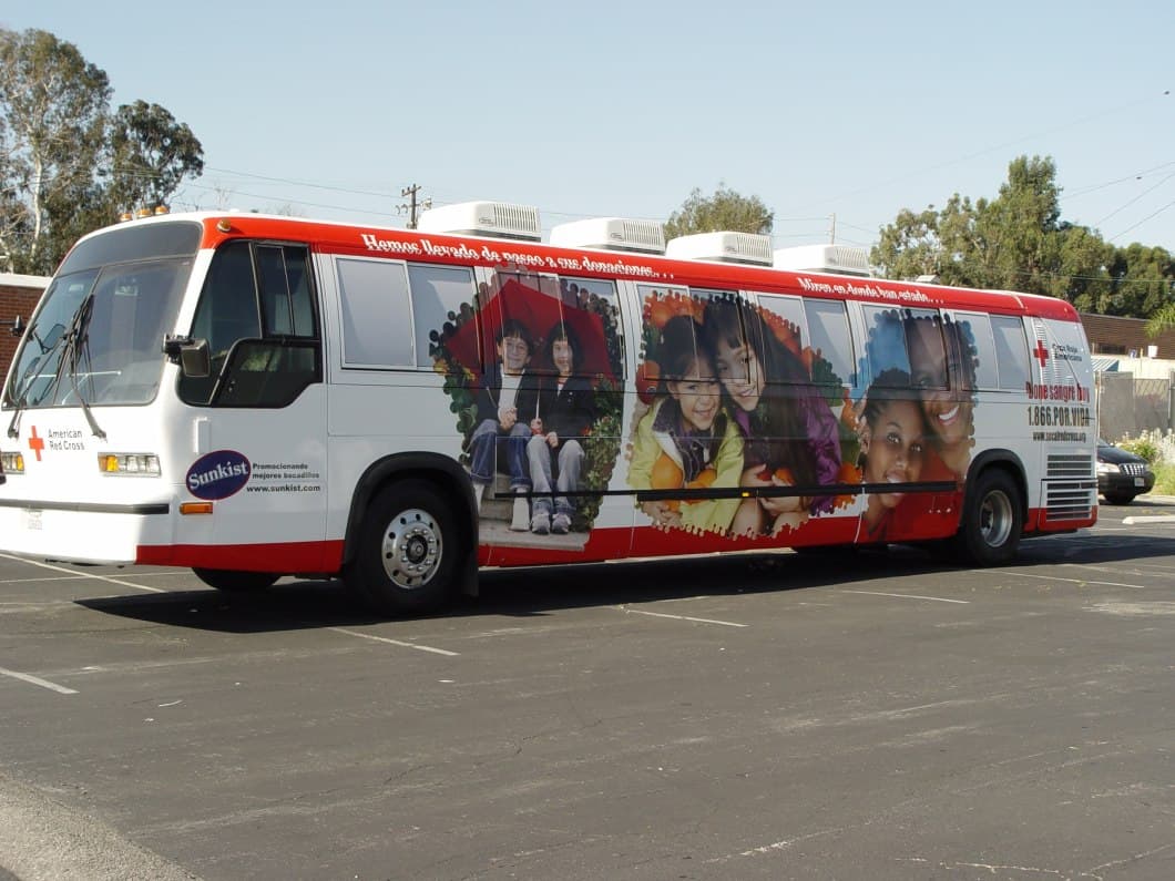 a red and white bus parked in a parking lot.