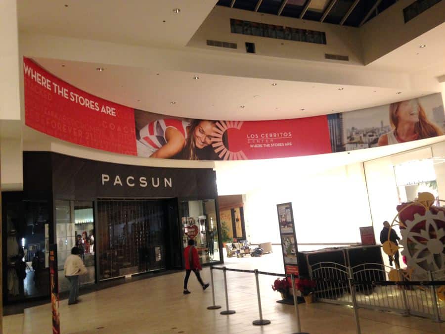 02 lcc south blkhd a woman walking through a shopping mall next to a red and white banner.