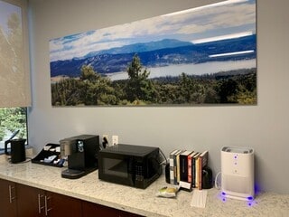 Art 2 a kitchen counter with a microwave, coffee maker and other items on it.