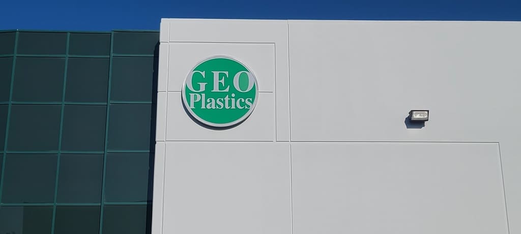 GEO Plastics sign-1 a white building with a green logo on it.