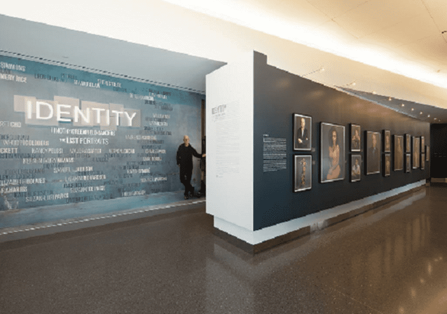 Identiity Wall a man standing in front of a wall with pictures on it.