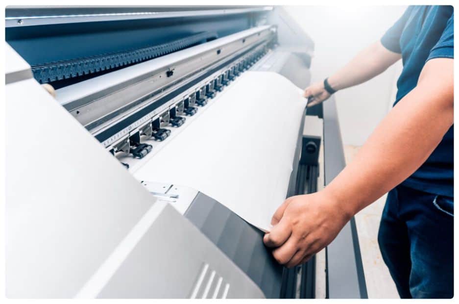 a person pulling a sheet of paper out of a machine.