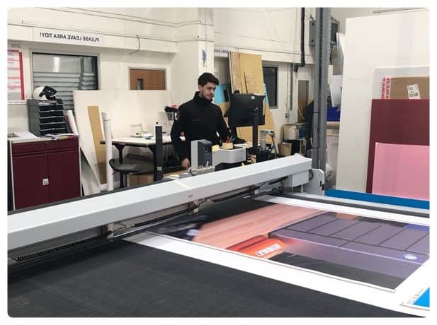 a man standing in front of a large screen printing machine.