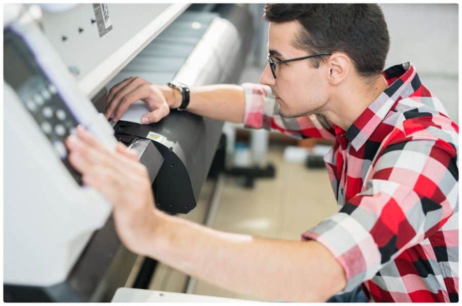a man in a red and black shirt is looking at a machine.