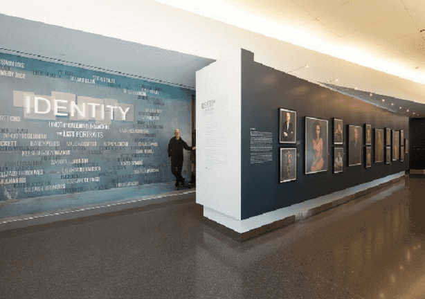 A man is standing in front of a wall with pictures on it. A man is standing in front of a wall with pictures on it.